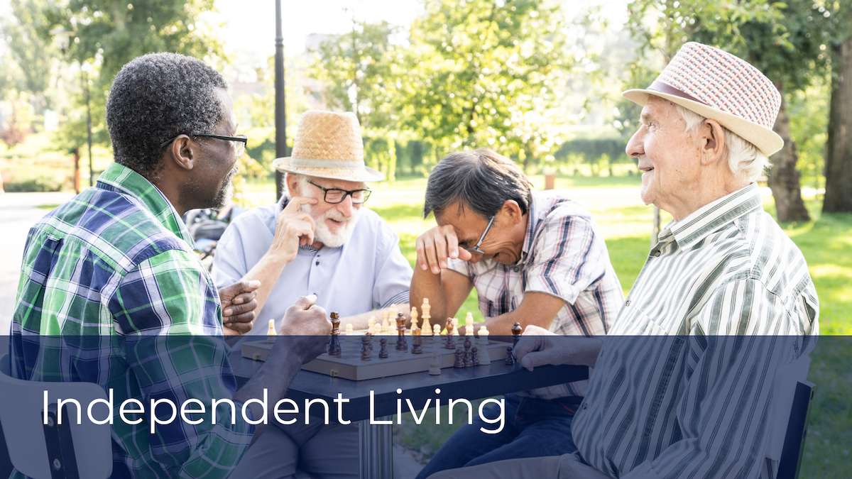 A group of senior men enjoying a game of chess outdoors, laughing and socializing.